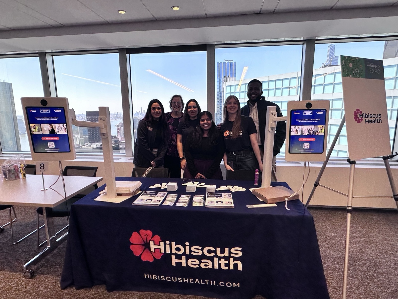 The Hibiscus Health team at a wellness expo booth with two Healthy Selfie kiosks